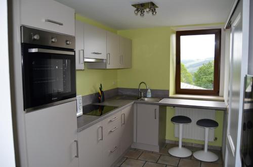 スタヴロにあるAu Petit Hの白いキャビネット、シンク、窓付きのキッチン