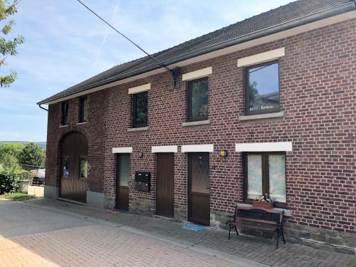 a brick building with a bench in front of it at Au Petit H in Stavelot