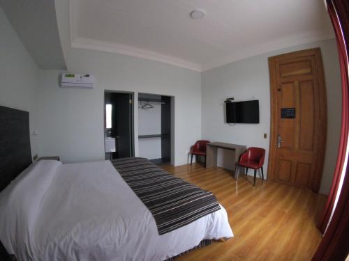 a bedroom with a bed and a desk and a mirror at Hotel Baquedano Boulevard in Iquique