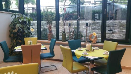 a dining room with tables and chairs and windows at Hotel Cristal in Nürnberg