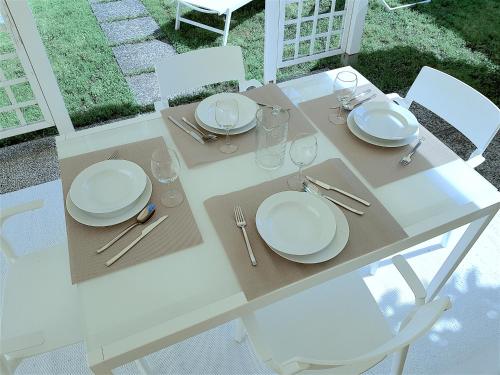 a white table with white plates and silverware on it at MINZONI94 - TwoBedroom+Garden in Lido di Camaiore