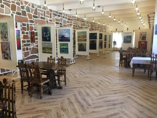 Habitación con mesas, sillas y pinturas en la pared. en Machanents Guest House en Vagharshapat