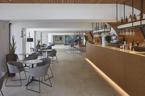 a restaurant with a bar with tables and chairs at Bordoy Alcudia Port Suites - Adults Only in Port d'Alcudia