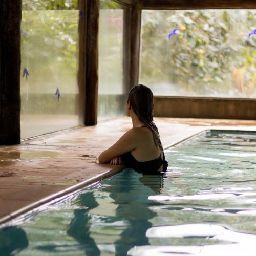 a woman is sitting in a swimming pool at Hotel Ponto de Luz in Joanópolis