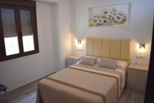 1 dormitorio con 2 camas y ventana en Iznájar Suites, en Iznájar