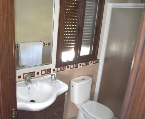 a bathroom with a sink and a toilet and a mirror at Iznájar Suites in Iznájar