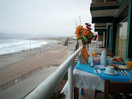 a table with a vase of flowers on a balcony overlooking the beach at Meflo Playa Grande in Chala