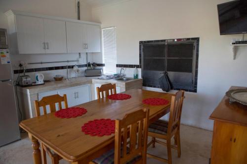 a kitchen with a wooden table with chairs and a refrigerator at Windfall Wine Farm in Robertson
