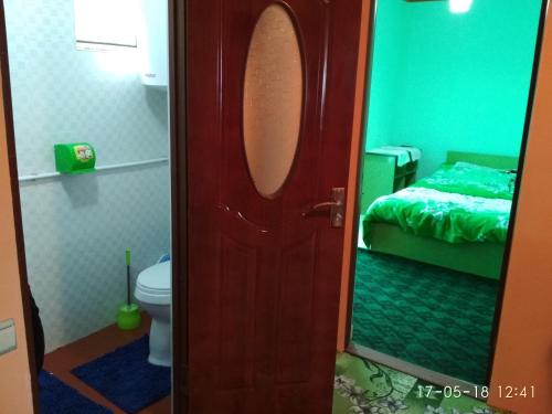 a bathroom with a toilet and a door with a mirror at Friendship (guest house)* in Arslanbob