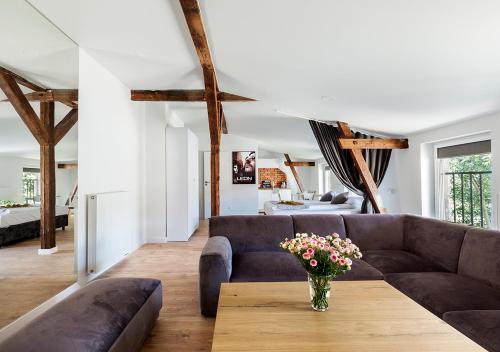 a living room with a couch and a vase of flowers on a table at Cinema Apartments in Poznań
