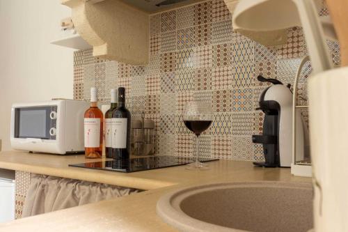 a kitchen counter with wine bottles and a glass of wine at Vicolo18 in Fasano