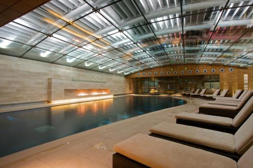 a swimming pool with lounge chairs in a building at Lucknam Park Hotel in Chippenham