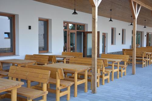 a cafeteria with wooden tables and benches and windows at Na Zeleném statku in Rašovice