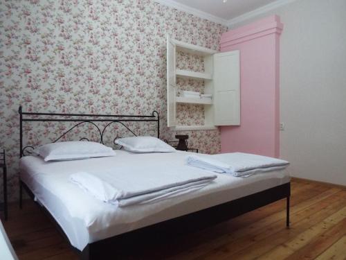 a bedroom with a bed with white sheets and pink wallpaper at Nino's House in Tsinandali