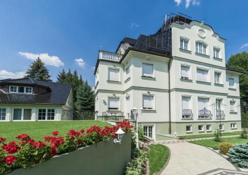 a large white building with red flowers in front of it at Hotel Villa am Waldschlösschen in Dresden