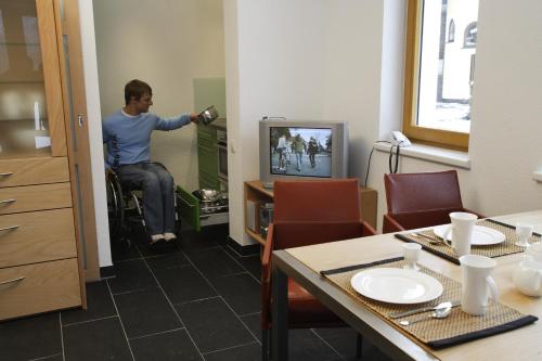 a man in a wheelchair watching a tv in a room at Ferienwohnungen Vier Jahreszeiten in Längenfeld