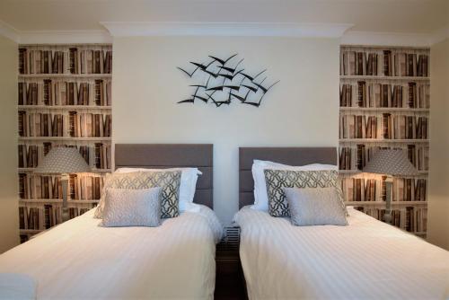 two beds in a room with book shelves at Meridian Way - Your Apartment in Bristol