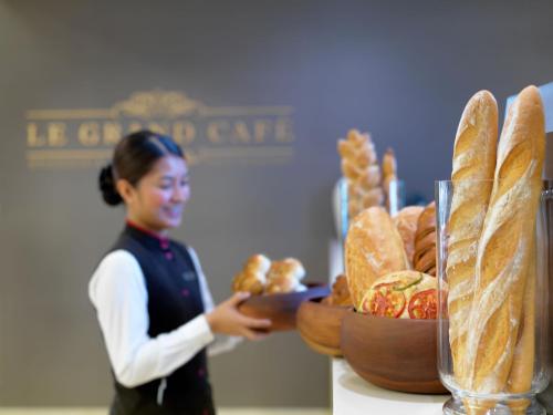 a woman standing next to a table with a tray of bread at Two Seasons Hotel & Apartments in Dubai