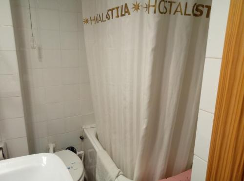 a bathroom with a toilet and a shower curtain at Hostal Residencia Castilla in Cuenca