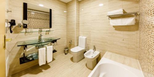 a bathroom with a toilet and a sink and a tub at Aurea Fatima Hotel Congress & Spa in Fátima