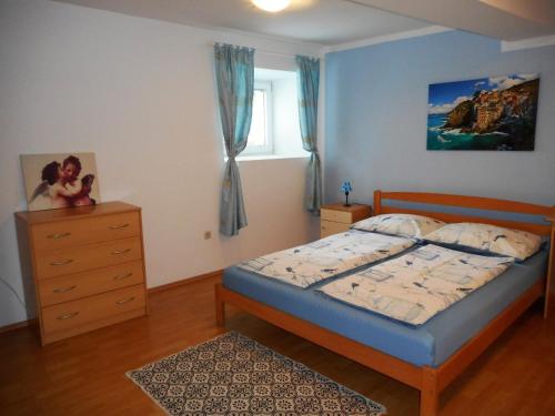 a bedroom with a bed and a dresser and a window at Apartman Sara in Matulji