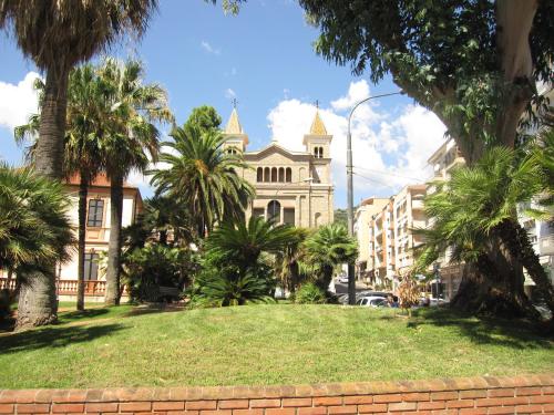 un edificio con un prato di fronte ad un edificio con palme di San Michele ad Arma di Taggia