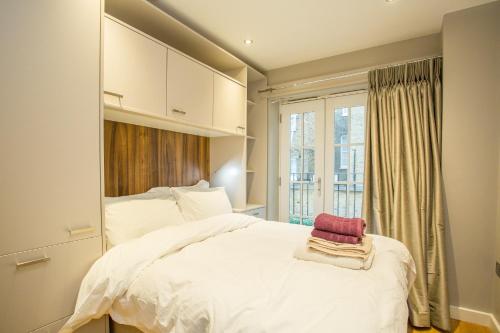 una camera da letto con un grande letto bianco e una finestra di The Escalier Mews - Bright 3BDR Home a Londra