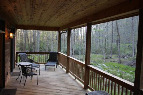 a porch of a cabin with chairs and a table at stayNantahala - Smoky Mountain Cabins in Aquone