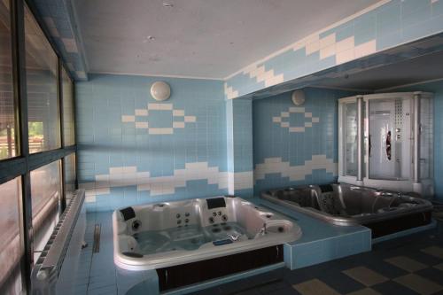a blue and white bathroom with a tub and a sink at Pensiunea Skiland in Muntele Băişorii