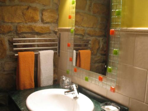 La salle de bains est pourvue d'un lavabo, d'un miroir et de serviettes. dans l'établissement Apartamentos Rurales KNICASIA, à Quintueles