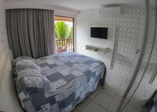 - une chambre avec un lit et un balcon avec une télévision dans l'établissement Nannai Residence, à Porto de Galinhas