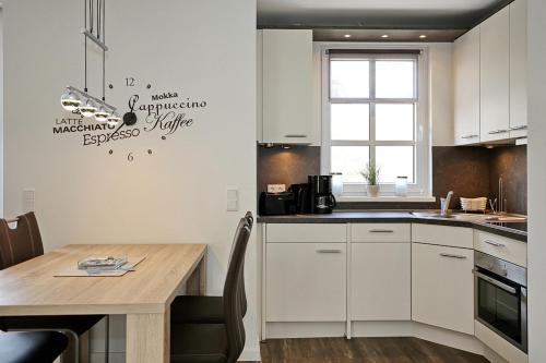 uma cozinha com armários brancos e uma mesa de madeira em Ferienwohnung Atlantis em Heiligendamm