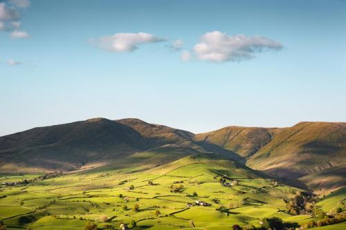 a painting of a green field with mountains in the background at The Black Bull Inn in Sedbergh