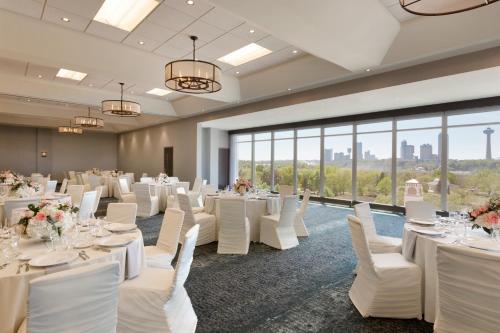 a banquet room with white tables and chairs and large windows at Hyatt Place Niagara Falls in Niagara Falls