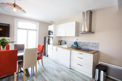 a kitchen with white cabinets and a table with chairs at Cap Canche in Étaples
