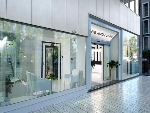 a building with glass doors and white chairs in it at Suite Hotel Elite in Bologna