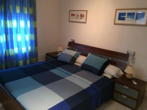 a bedroom with a blue and white bed and a window at Casas Blancas Bungalow 45 in L’Alfàs del Pi