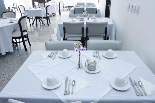 ein Esszimmer mit weißen Tischen und Stühlen mit Besteck in der Unterkunft Blue Open Hotel in Erechim