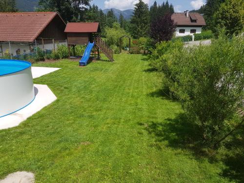 a yard with a playground and a blue slide at Holzhaus in Hinterstoder in Hinterstoder