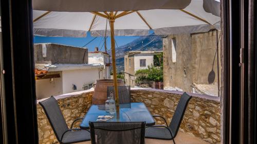 einen Tisch und Stühle auf einem Balkon mit Sonnenschirm in der Unterkunft Nivritos Traditional Homes in Nívritos