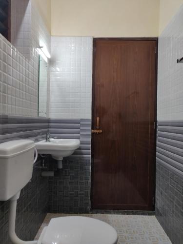 a bathroom with a toilet and a sink and a wooden door at Hotel Wins in Kanyakumari