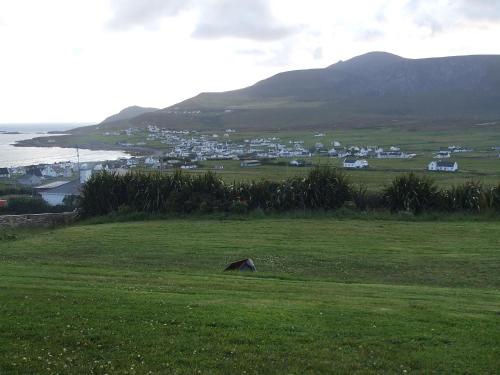 a field of green grass with a town in the background at Achill West Coast House in Dooagh