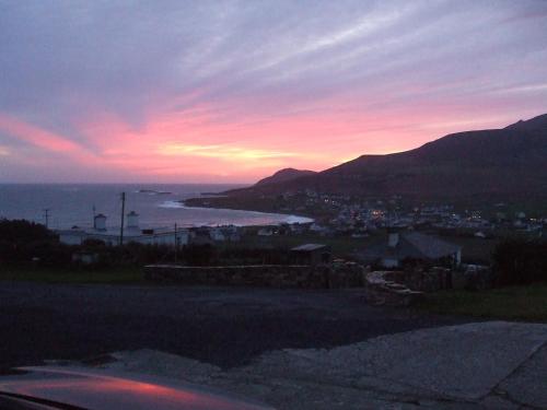 a sunset view of the ocean and a city at Achill West Coast House in Dooagh