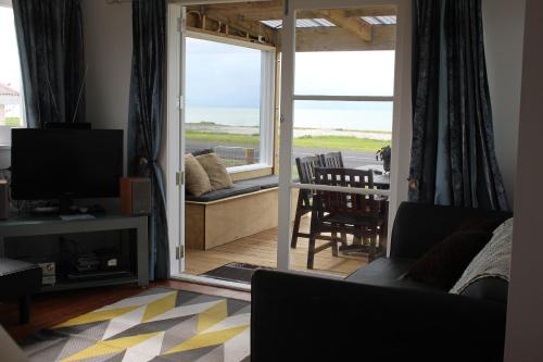 un soggiorno con TV e tavolo con sedie di Sea Urchin Cottage a Miranda