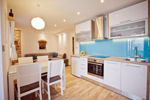 una cocina con armarios blancos y una mesa con sillas. en Paradise Stone Apartments, en Bol