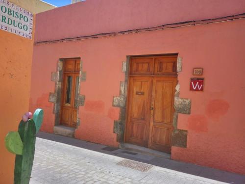 a red building with two wooden doors and a cactus at Artisan´s House in Agüimes