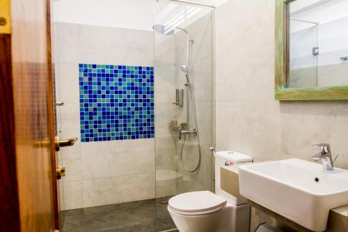 a bathroom with a shower and a toilet and a sink at Lazy Koala in Hikkaduwa