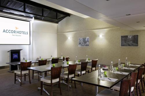 a dining room with tables and chairs and a screen at Novotel Queenstown Lakeside in Queenstown