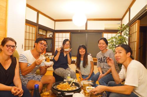 a group of people sitting on a couch eating food at 晴家(HALELUYA) Guest House in Fujikawaguchiko