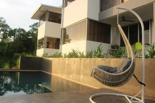 a hammock sitting on the side of a house next to a pool at Horizon Lodge Potrero in Potrero